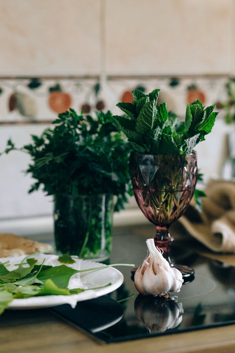 Aesthetic herbal arrangement with garlic, fresh mint, and parsley in a kitchen.